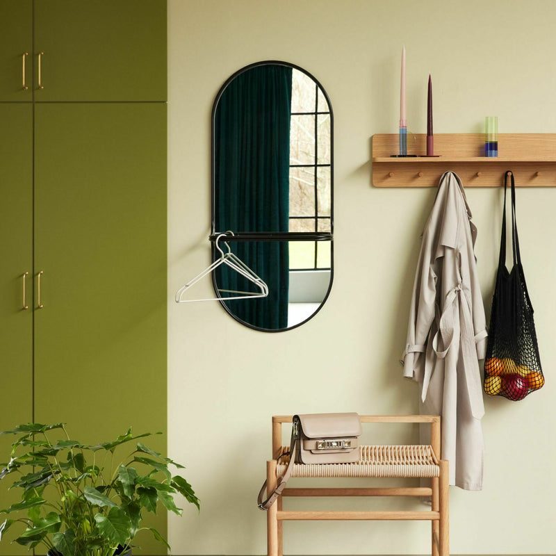 Porte-manteau Hübsch en chêne à tablette et sept crochets dans une entrée claire, au-dessus d'un banc en bois, à côté d'un miroir ovale